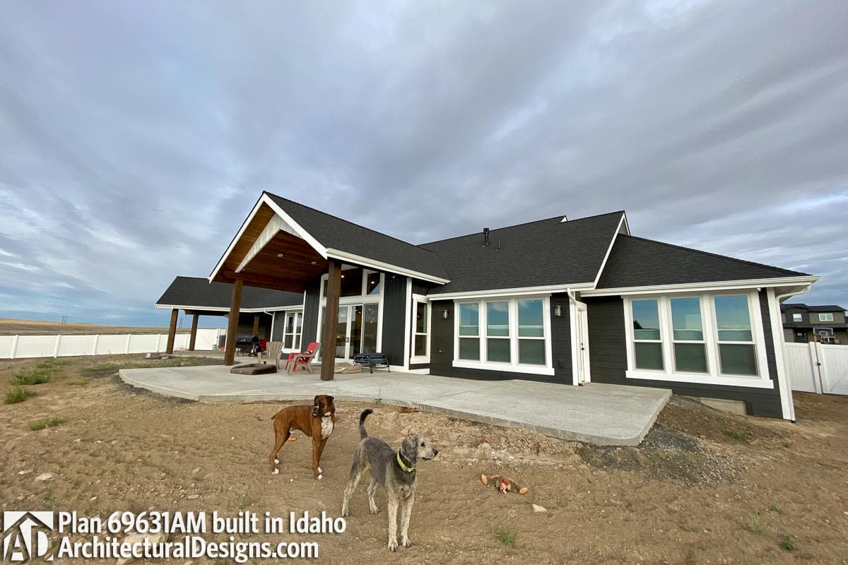 House plan exterior with covered patio, gabled rooflines, and numerous windows.