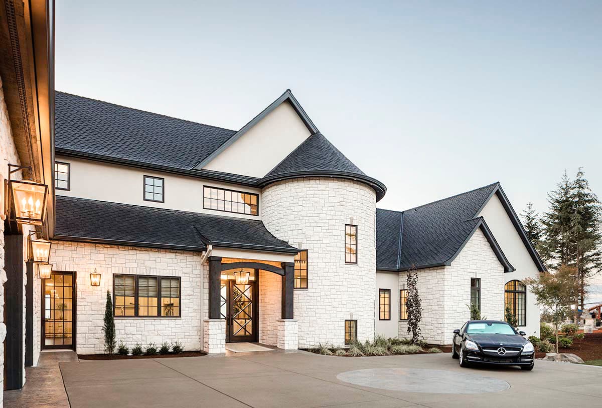 House plan exterior featuring white stone facade, prominent turrets, arched entry, and multiple gables.