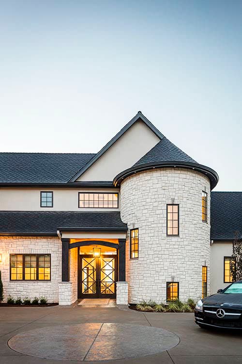 House plan exterior with stone facade, prominent turret, arched entryway with double doors, and multi-story gables.