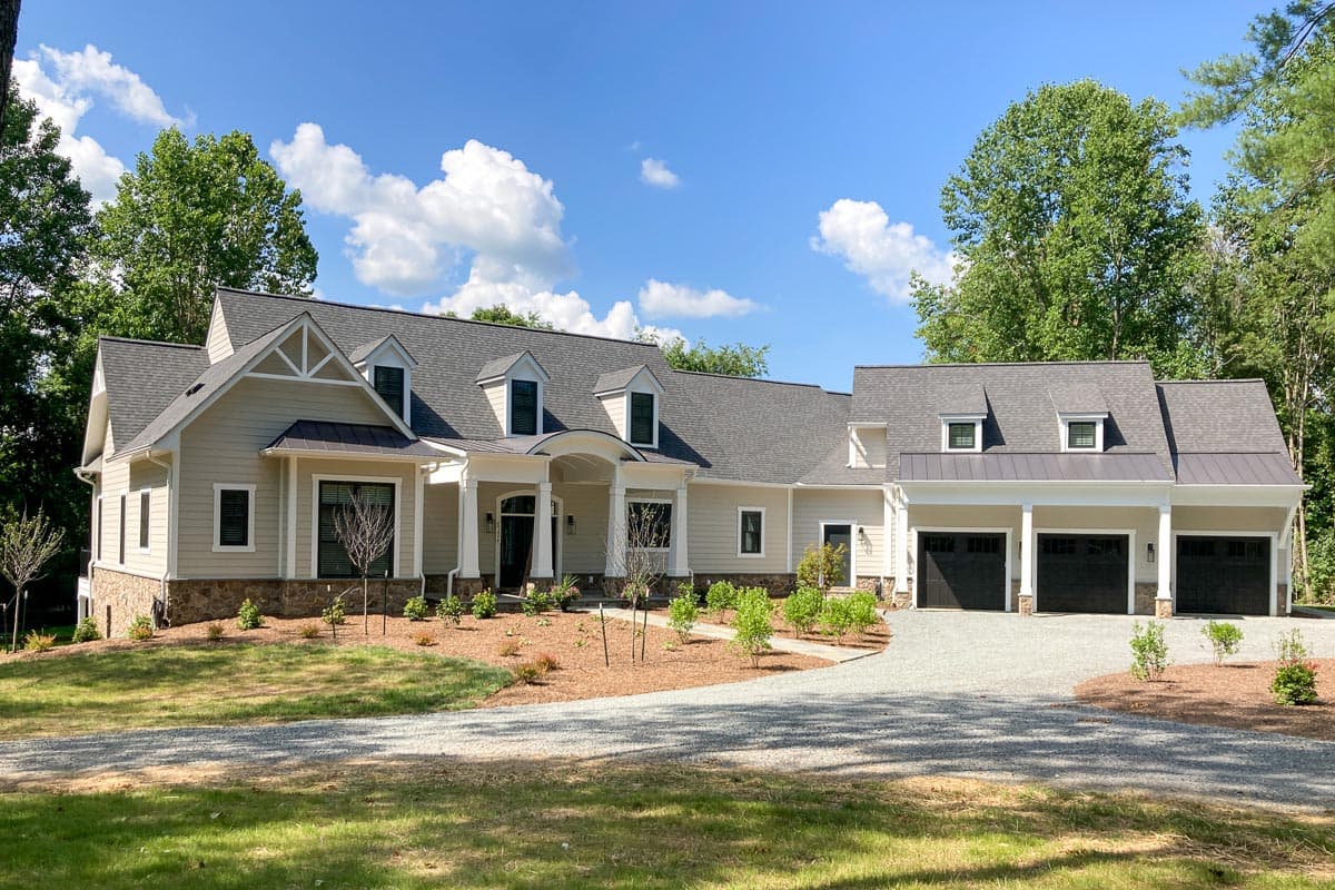 House plan exterior: Single-story home with a covered entrance, gables, dormers, stone accents, and a three-car garage.