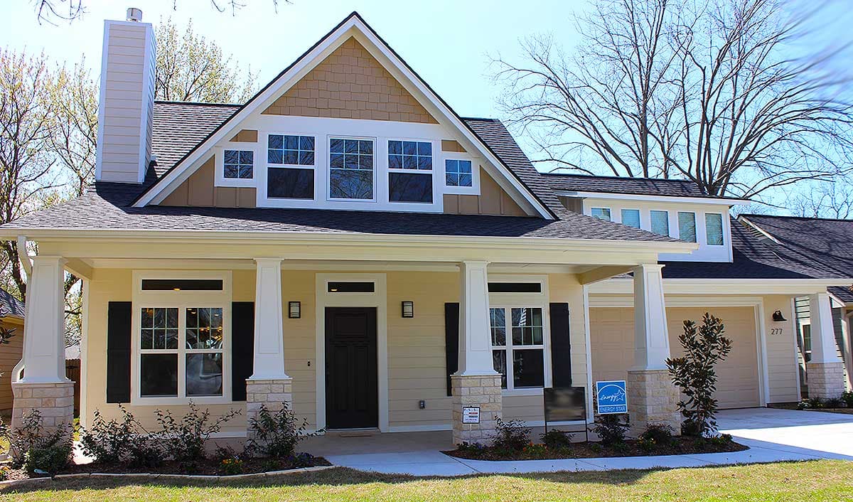 House plan exterior. Craftsman style, one-story home with front porch, gabled roof, and dormers. Attached garage on right side.