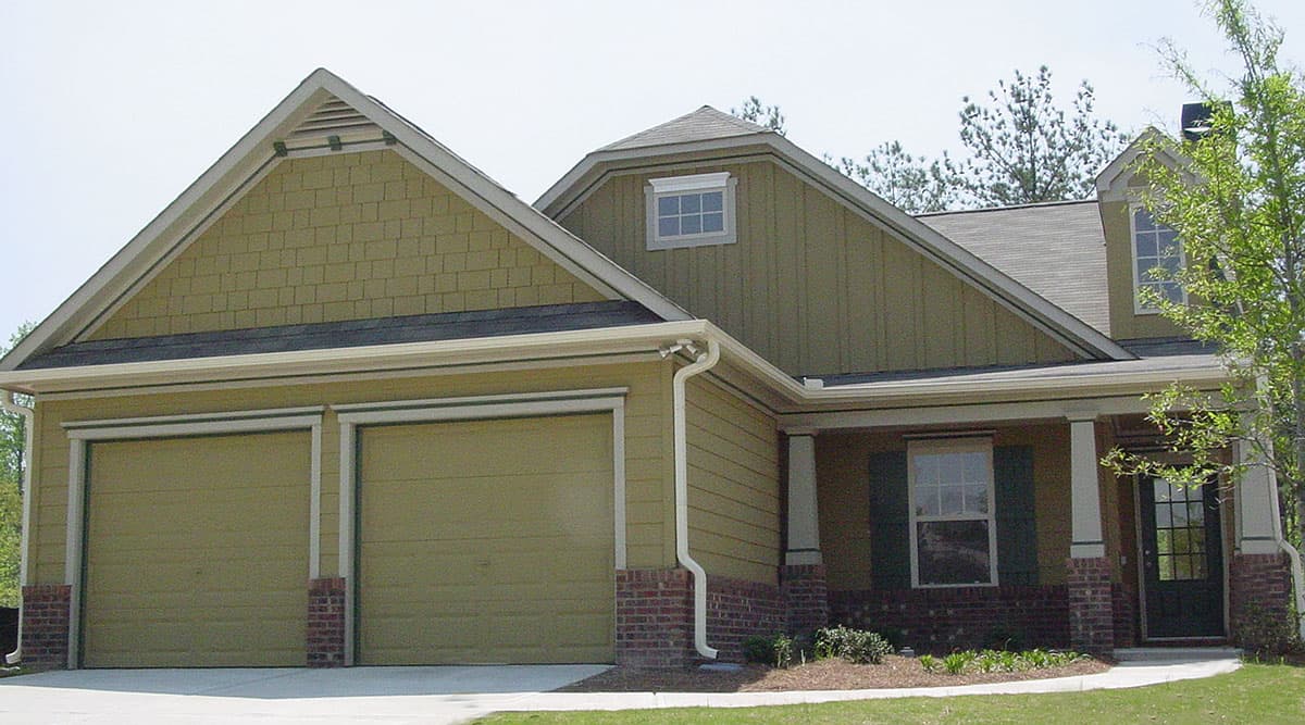 House plan exterior: one-story home with two-car garage, gables, dormer window, and covered front porch.