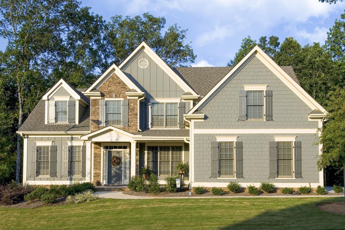 House plan exterior. Two-story home with a gabled roof, stone facade accent, and multiple dormers. Includes shutters on the windows.