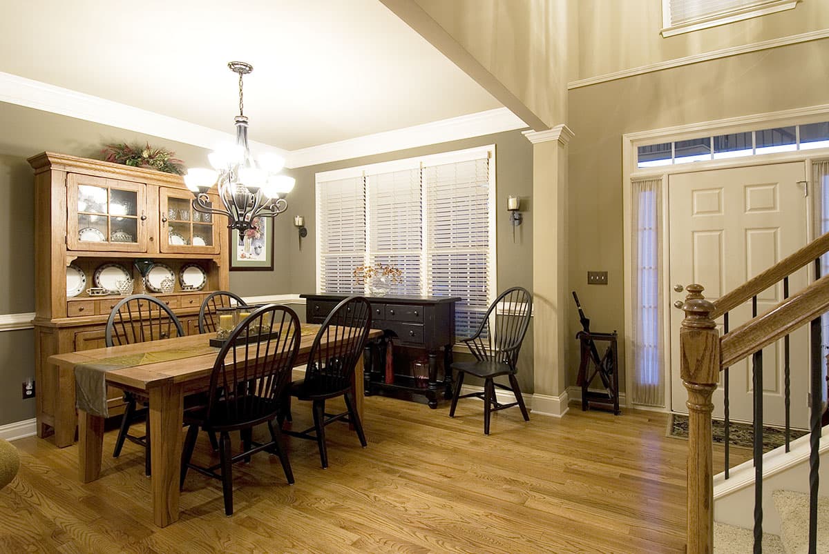 Formal dining room with wooden hutch, table and chairs, view of entry staircase and front door.
