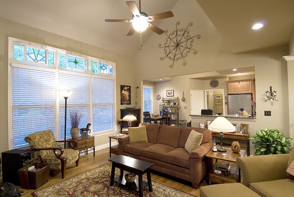 Great room with vaulted ceiling, fireplace, sofa, and pass-through to kitchen with stainless steel appliances.
