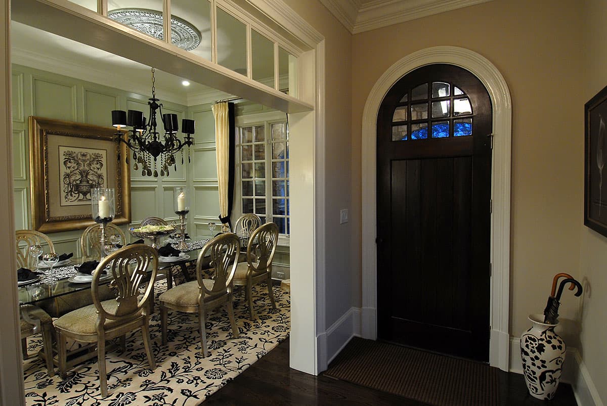 Interior view of a dining room with a large dark wood arched door and dining table set for a meal.