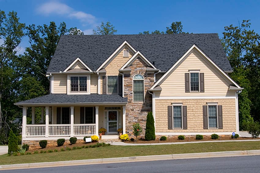 House plan exterior with a wrap-around porch, stone accents, and multiple gables. Two stories.