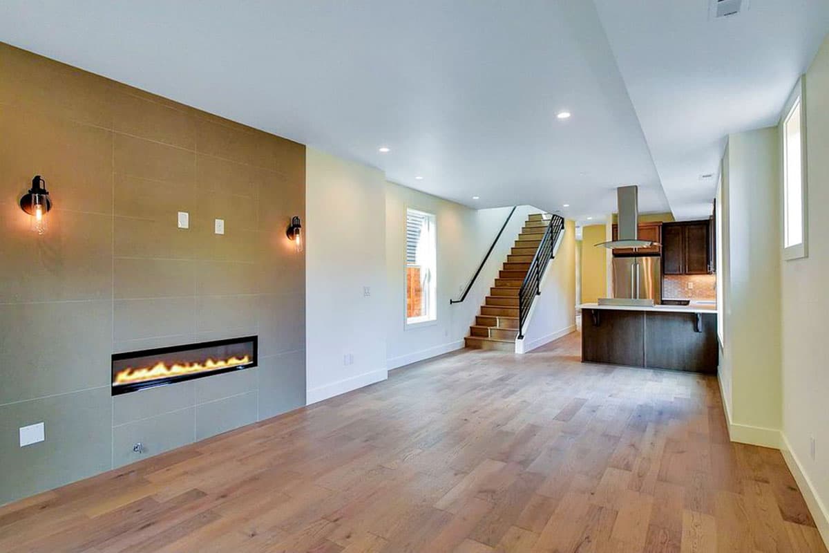 Open concept living area with modern fireplace, kitchen island, and stairs leading to upper level.