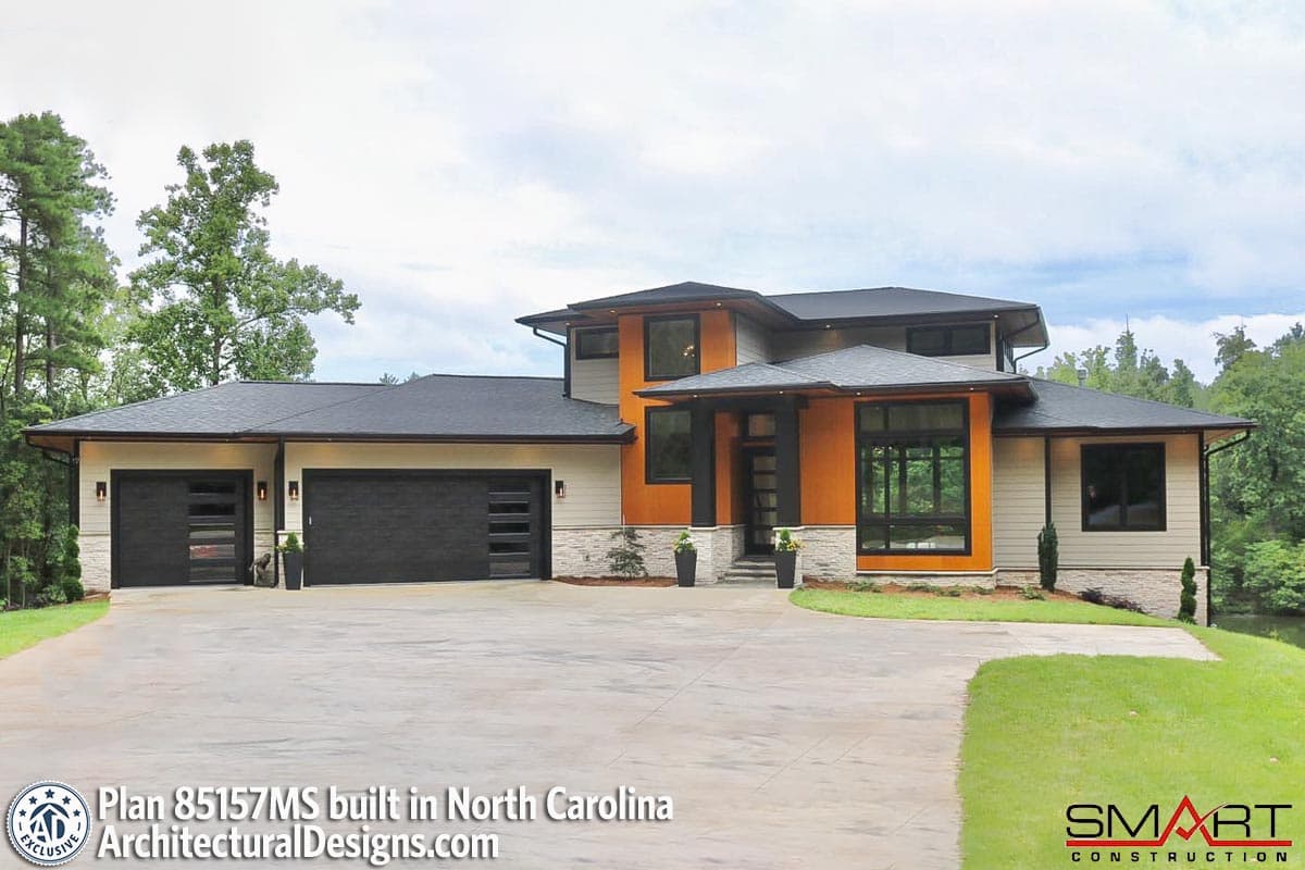 Modern house plan exterior with a three-car garage, stacked gables, and a prominent orange accent section.