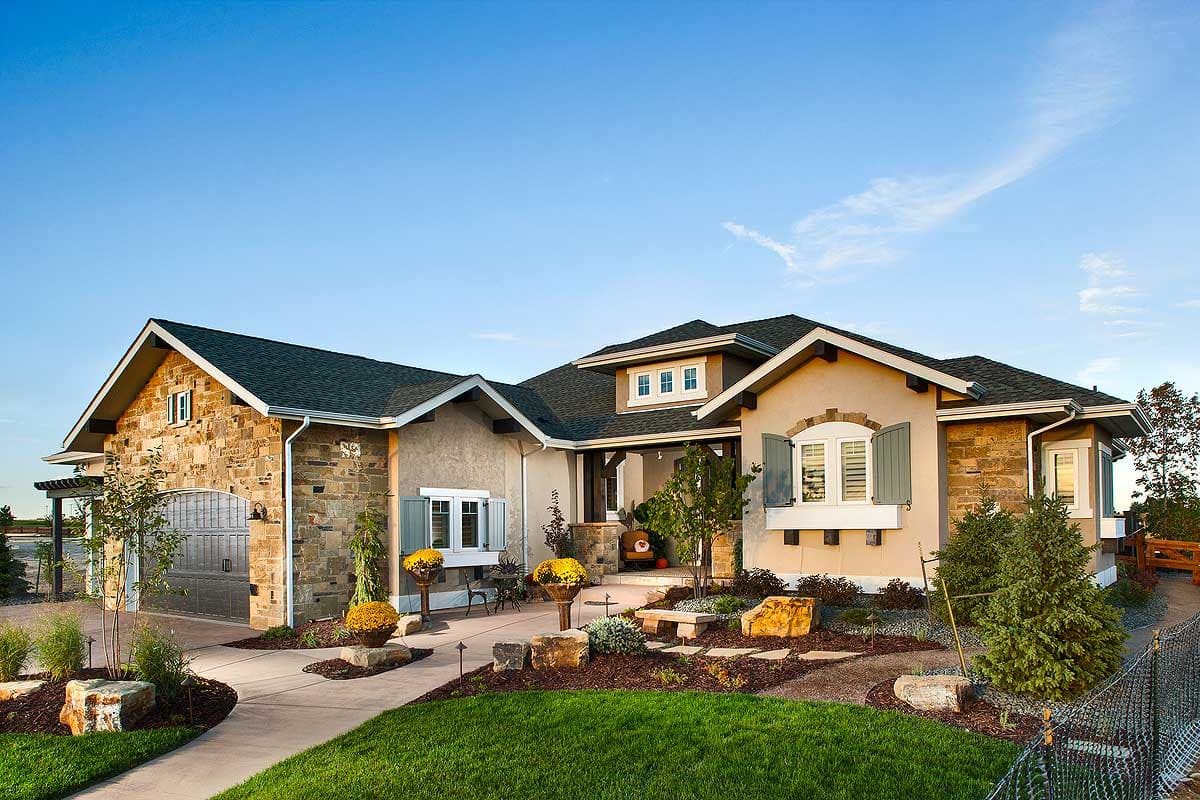 House plan exterior with stone and stucco facade, featuring multiple gables, dormers, and a detached garage with an arched garage door.