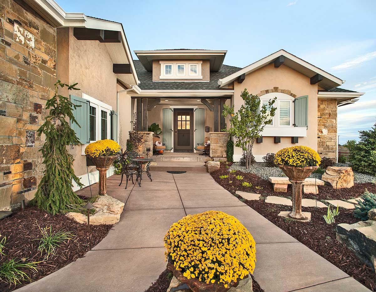 House plan exterior, two-story, stucco and stone facade, covered entry, gabled dormer, and exterior shutters.