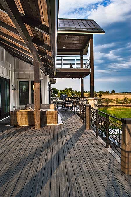 Modern Farmhouse house plan exterior with two-story deck, board and batten siding, and exposed timber roof beams.