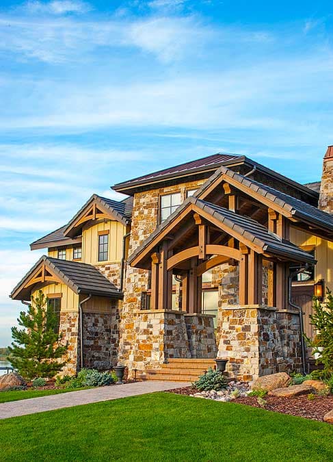 Craftsman house plan exterior with stone and wood siding, covered entry with timber framing, and multiple gables.