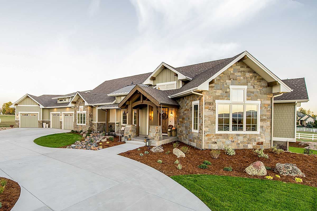 Craftsman style house plan exterior with stone facade, exposed beams, multi-level rooflines, and a three-car garage.