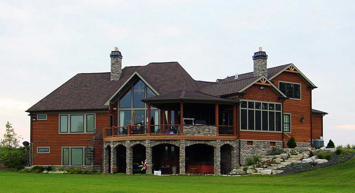 House plan exterior: Two-story home with cedar siding, stone accents, multiple gables, covered porch, and large windows.