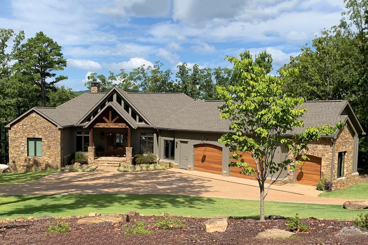 House plan exterior: Craftsman-style, one-story home with stone accents, gabled entry porch, and three-car garage.