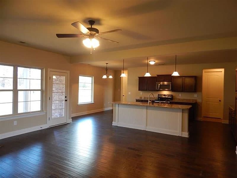 Interior view of open-concept living space with kitchen island, dark cabinets, and large windows.