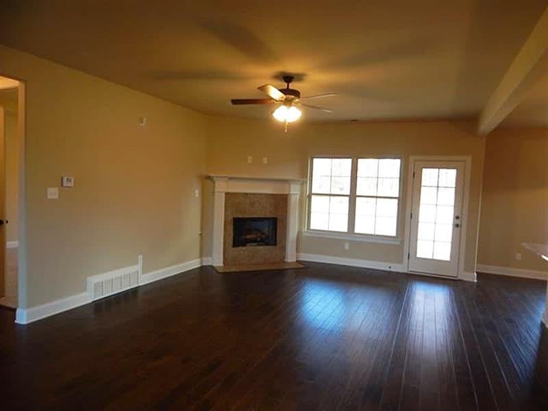 Interior view: Great room with fireplace, three windows, glass door, and ceiling fan.
