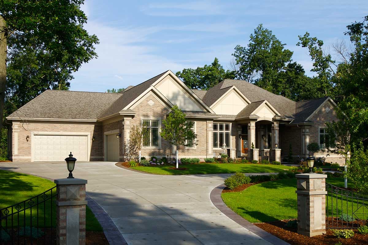 House plan exterior. Two-story brick home with gabled roof, front porch with columns, and attached garage with two bays.