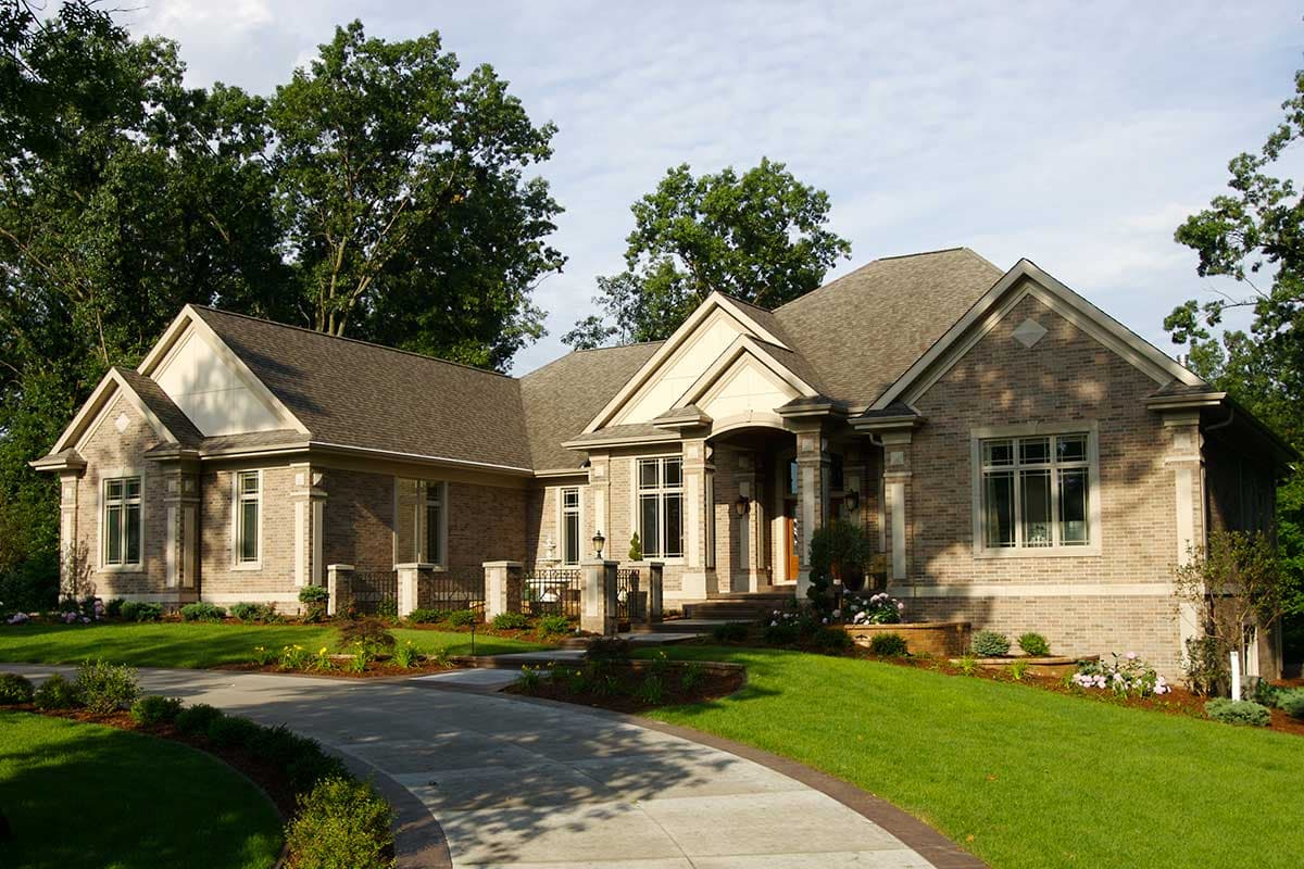 House plan exterior: Brick home with gabled dormers, covered entrance with columns, and multi-level rooflines.