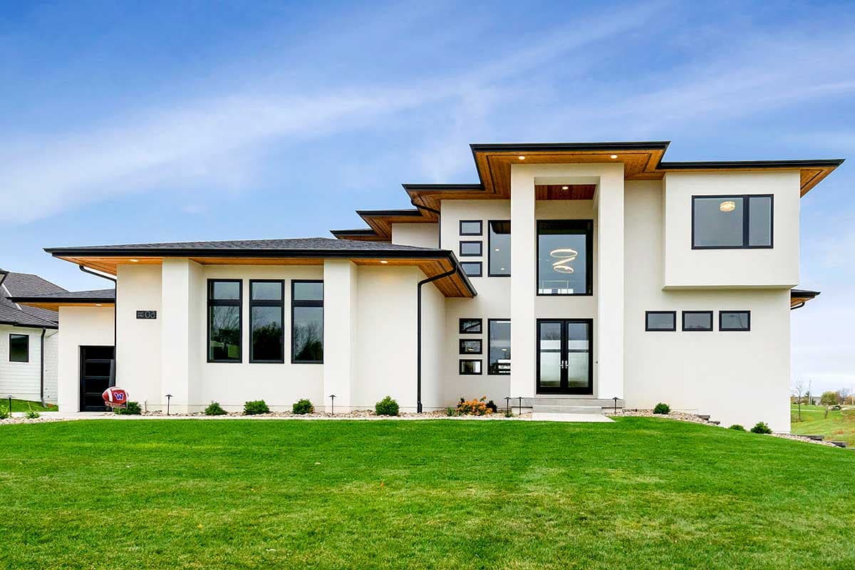 House plan exterior with modern style, two stories, flat rooflines with wood soffits, and large windows. Includes black framed windows and doors.