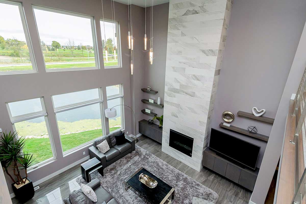 Great room with floor-to-ceiling windows, a stone fireplace, and open loft.