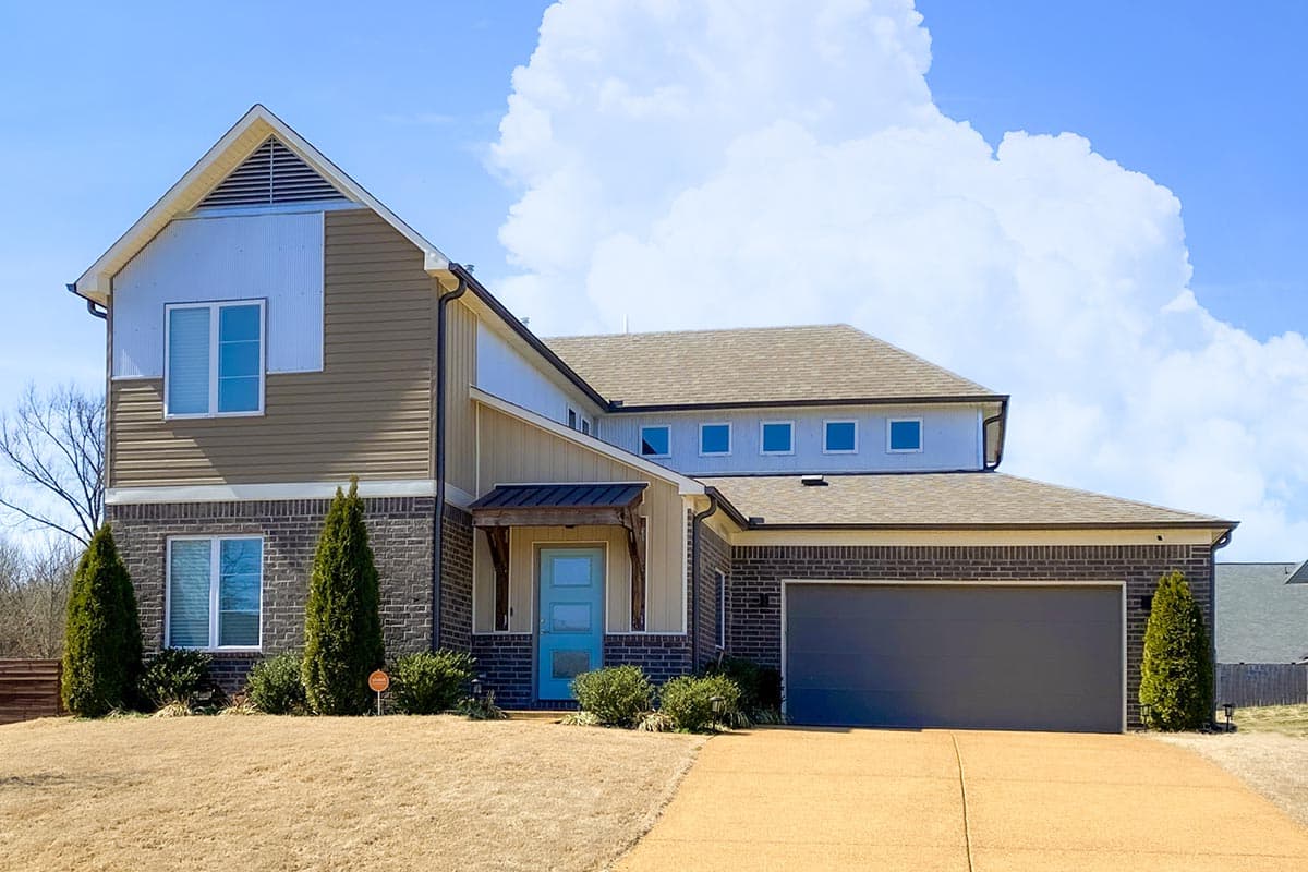 House plan exterior: Two-story Modern Farmhouse with gable roof, brick base, siding, covered entry, and attached garage.