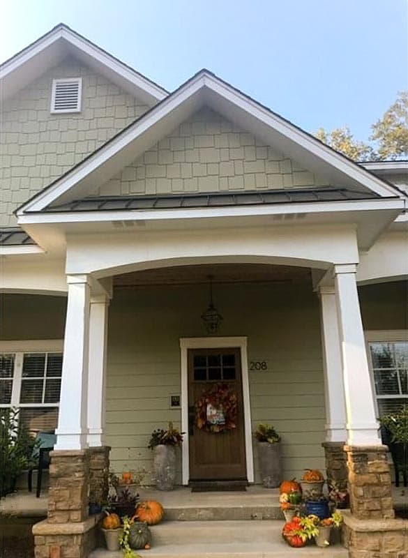 House plan exterior: Craftsman style, two-story with a covered porch supported by stone-clad columns, gabled dormers, and shingle siding.