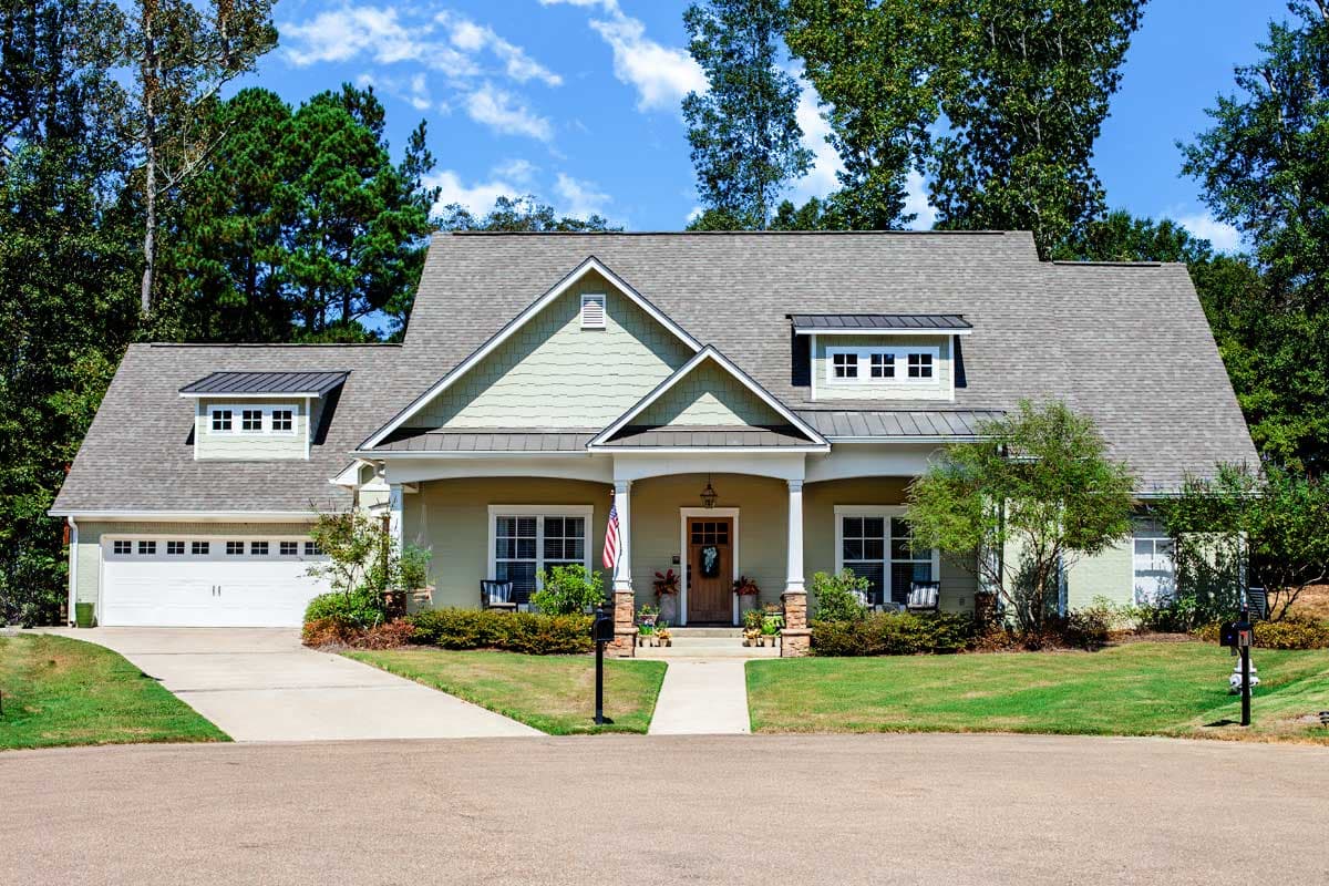 House plan exterior with Craftsman style, one-story. Features include a front porch with columns, gables, and a garage with dormers.