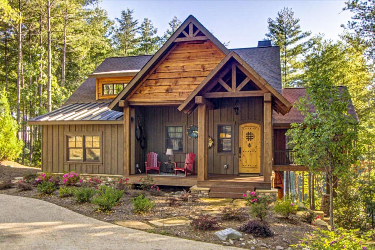 House plan exterior. Two-story cabin style with gabled roof, timber frame entry porch, and exposed rafter tails.