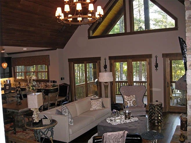 Great room with vaulted, wood-paneled ceiling, large windows, and exposed beams. Open to kitchen and dining areas.