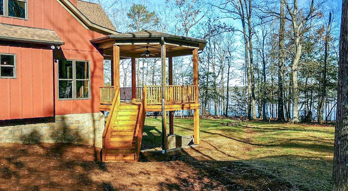 House plan exterior with wood siding, stone foundation, multi-level deck, and outdoor staircase.