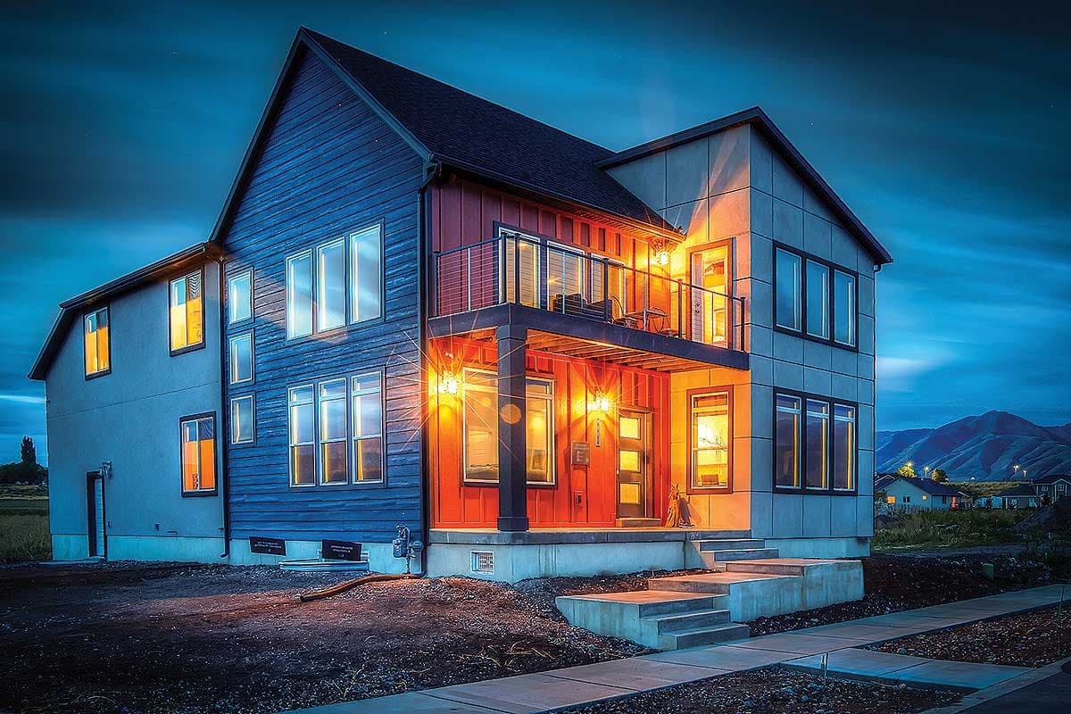 Modern two-story house plan exterior with vertical siding, multiple gables, and a cantilevered balcony.