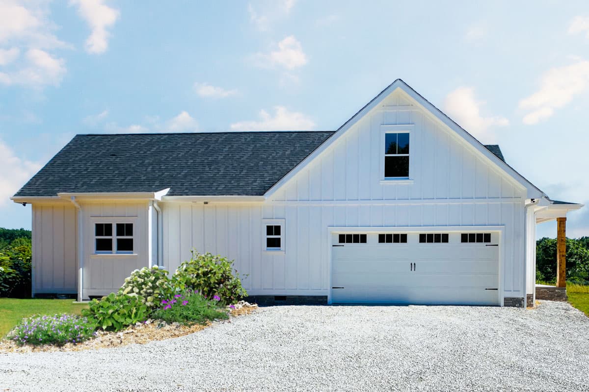 House plan exterior: Modern Farmhouse style, one-story, white board and batten siding, attached garage, gabled dormer above garage.