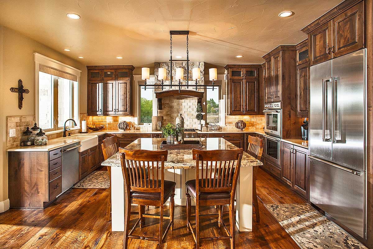 Kitchen interior with dark wood cabinets, granite island, stainless steel appliances, and brick backsplash.