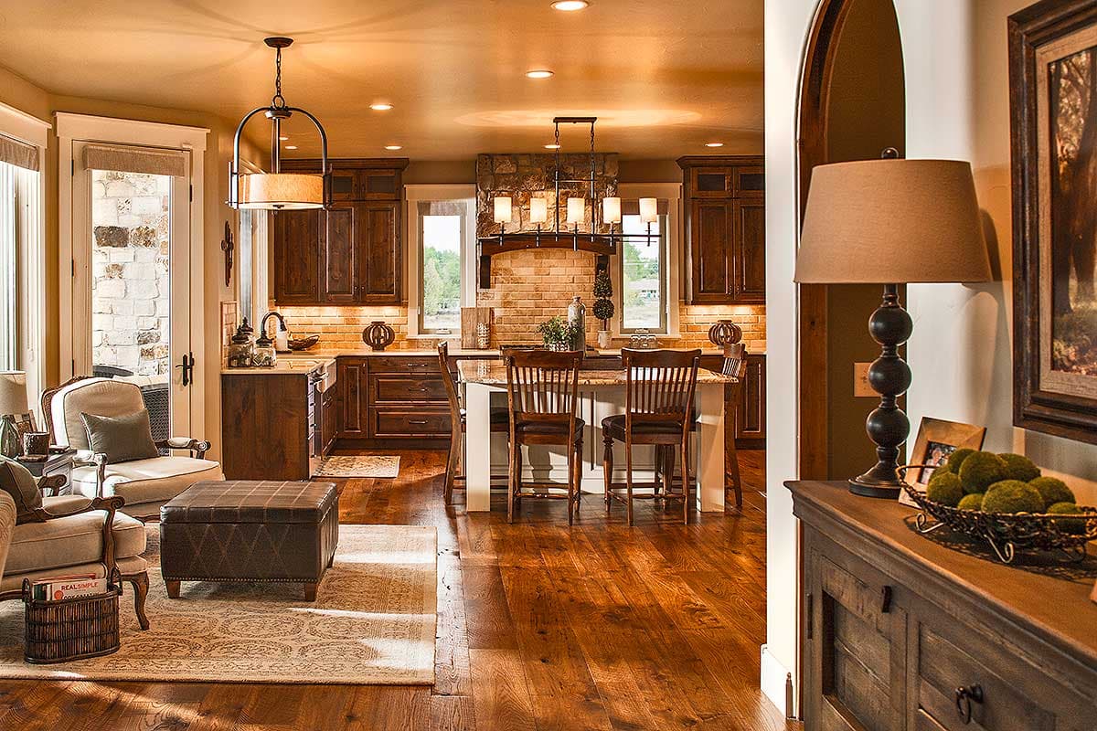 Open concept kitchen and living area with a large island, stone range hood, and dark wood cabinetry.