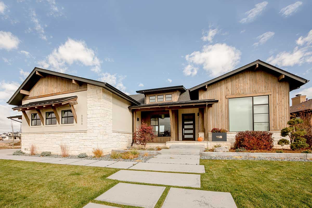 House plan exterior with wood siding and stone accents. Features a covered entry, multiple gables, and large windows. Modern design with clean lines.