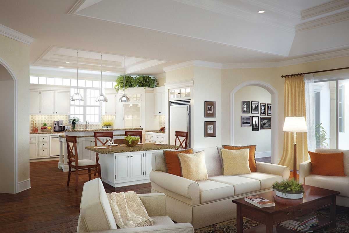 Open-concept living area with kitchen island, seating area, and archway to dining room. Tray ceiling detail.