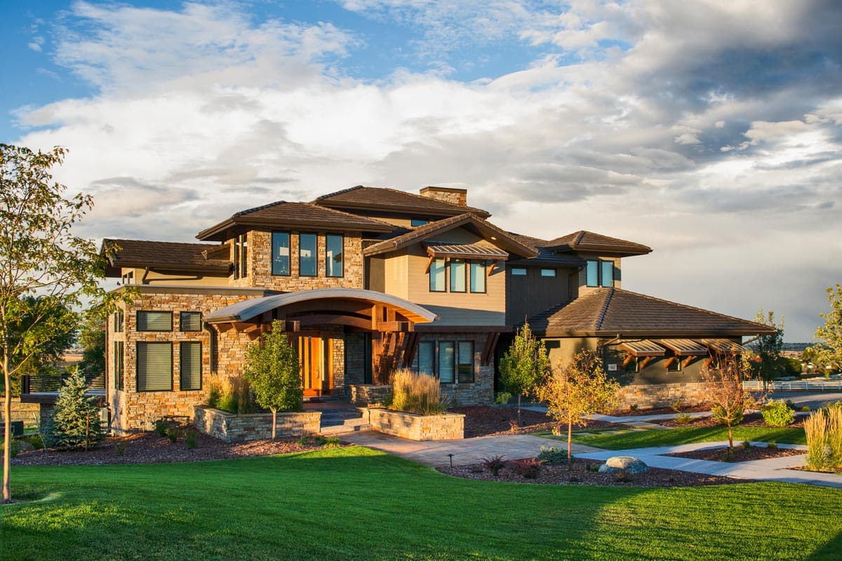 House plan exterior with stone and siding facade, curved entry portico, multiple gabled rooflines, and multiple stories.
