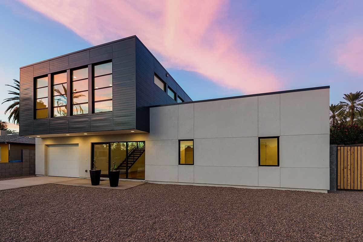 House plan exterior with modern design. Two-story structure featuring a cantilevered upper level, large windows, and a flat roofline. Attached garage.