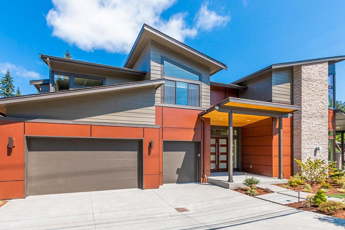 Modern house exterior with intersecting rooflines, stone accent wall, and two garage doors.