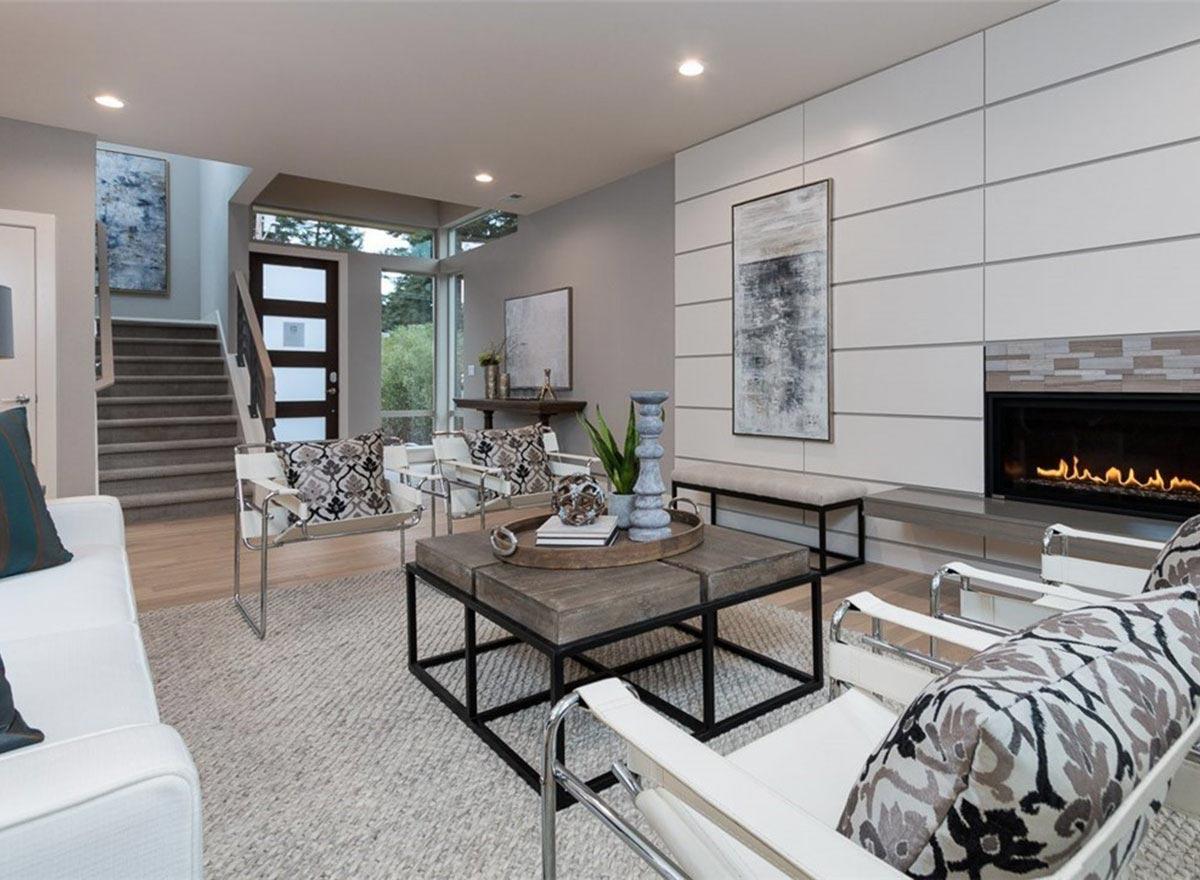 Interior rendering of a living room with a modern fireplace, geometric-patterned accent wall, glass-paneled door, and staircase.