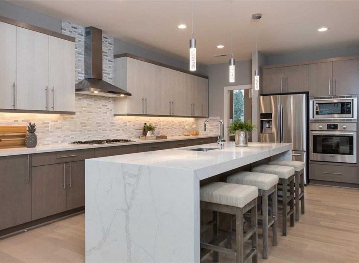 Contemporary kitchen with a large island, two-tone cabinetry, stainless steel appliances, and mosaic tile backsplash.