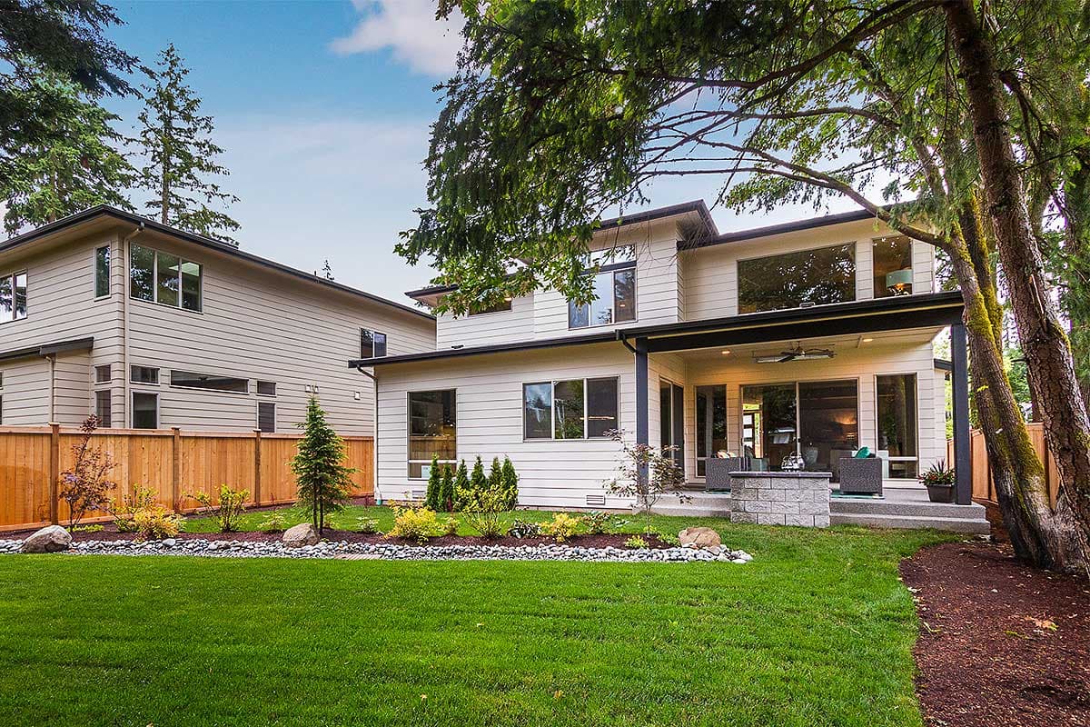 Modern two-story house plan exterior with lap siding, large windows, covered patio, and outdoor fireplace.