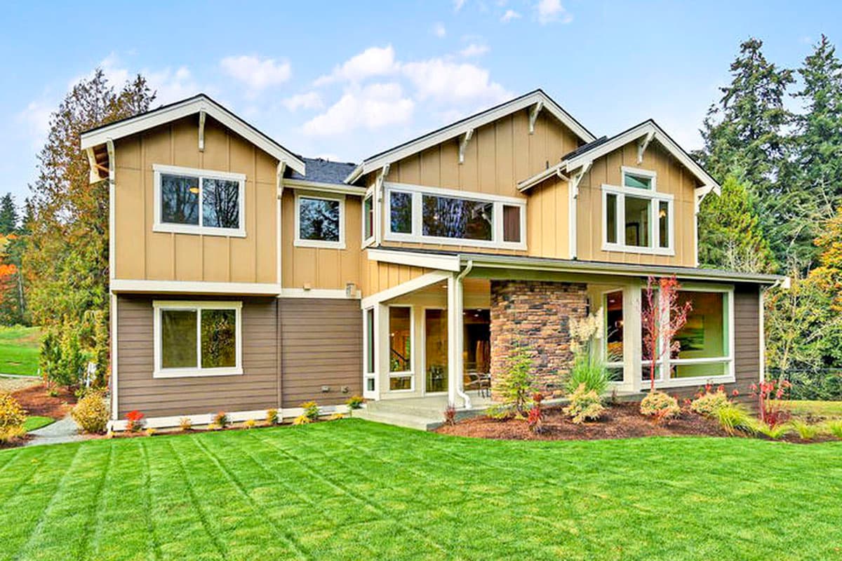 Two-story house plan exterior with multiple gables, stone column accents, covered entry, and large windows.