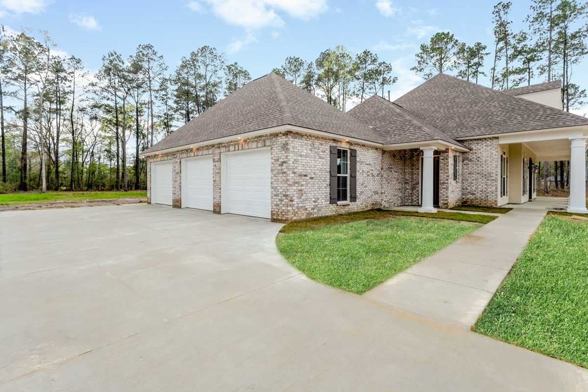 House plan exterior with brick facade, three-car garage, covered entryway with columns, and hip rooflines.