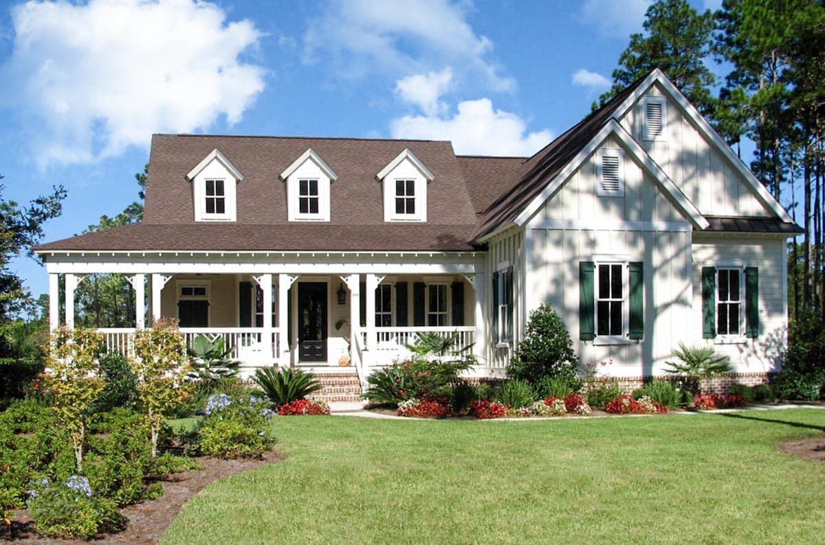 House plan exterior. Craftsman style, one-story home with a wraparound porch, three dormers, and a gabled roofline.
