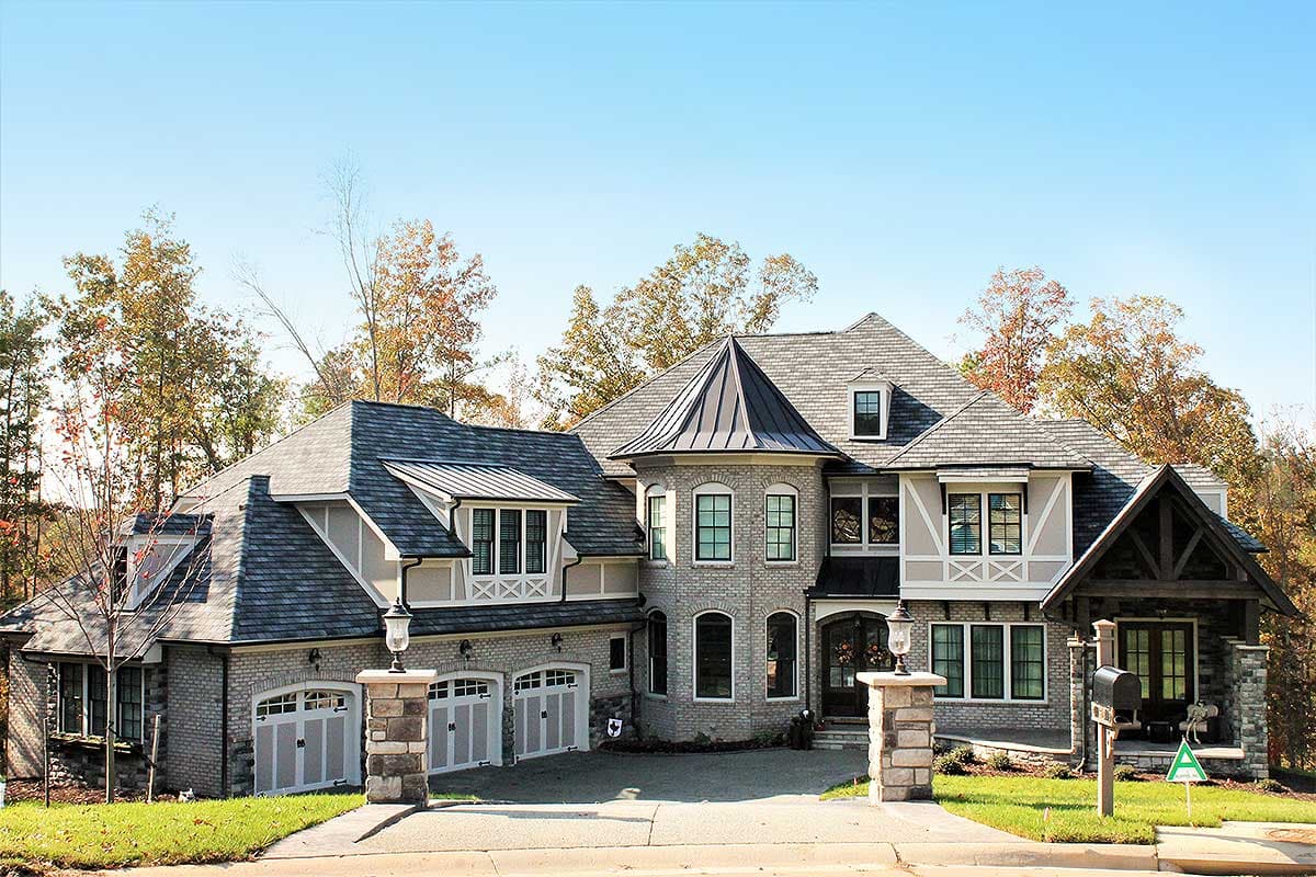 House plan exterior: Two-story home with a three-car garage, multiple gables, dormers, and a prominent turret.