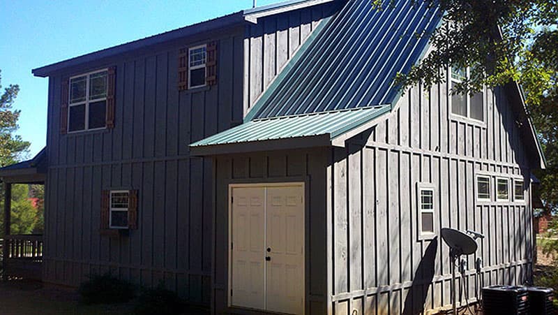 House plan exterior: Two-story board and batten siding, metal roof, double doors, and multiple windows.