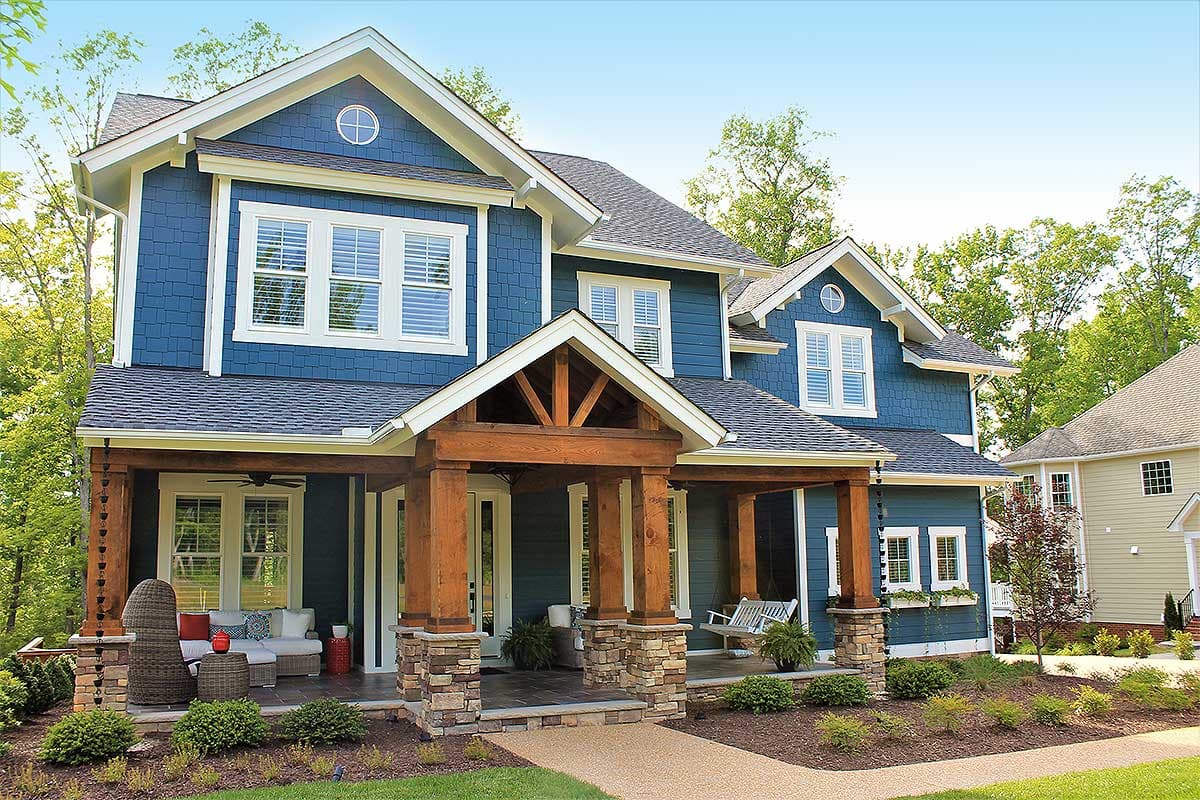 House plan exterior. Two-story Craftsman home with a covered porch supported by stone and wood columns, gables, and dormers.